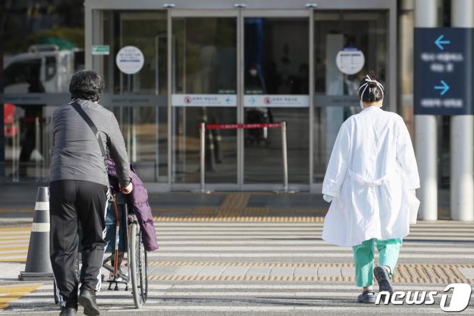 전공의들의 집단행동이 한 달째를 맞은 18일 서울의 한 대학병원에서 환자와 의료진이 나란히 길을 건너 병원으로 향하고 있다.  2024.3.18/뉴스1 ⓒ News1 민경석 기자