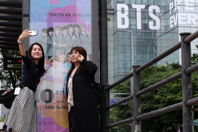 방탄소년단(BTS) 촬영 현장에서 스태프로 일하게 해주겠다고 팬을 속여 수억원대 금품을 뜯어낸 40대가 실형에 처했다. 사진은 지난해 6월12일 서울 용산구 하이브 사옥 앞에서 BTS 데뷔 10주년을 축하하는 광고판을 배경으로 기념사진을 찍고 있는 해외팬들. /사진=뉴스1