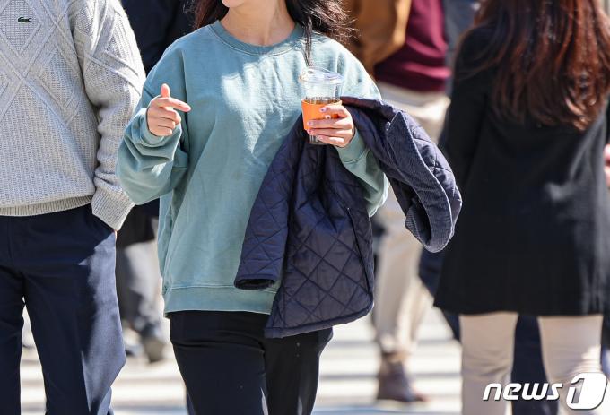 서울 시내 한 거리에서 시민이 외투를 벗고 길을 지나고 있다. 2024.3.13/뉴스1 ⓒ News1 김도우 기자