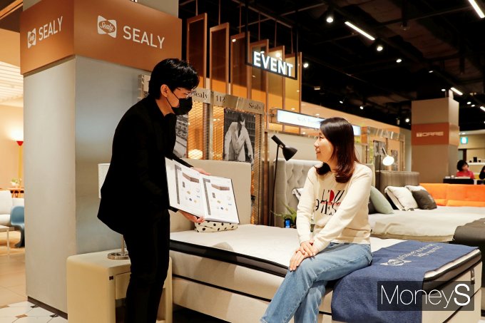 광주신세계 본관 8층 씰리침대 매장을 찾은 여성 고객이 직원으로부터 상품 설명을 듣고 있다/사진=광주신세계 제공.