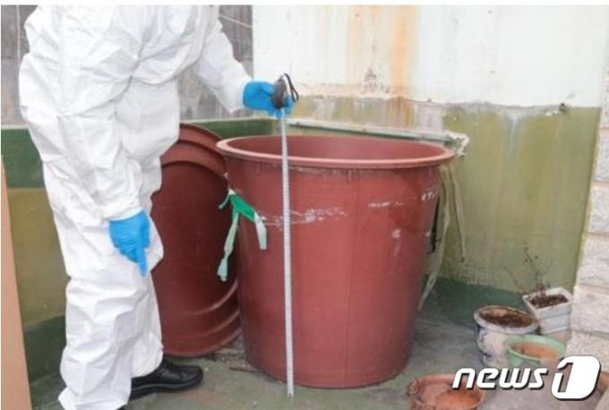 2019년 3월 부산 남부경찰서 형사들이 4년 3개월 가량 시신을 담아 두었던 빨간 고무통 크기를 재고 있다. (부산 경찰청 제공) ⓒ 뉴스1
