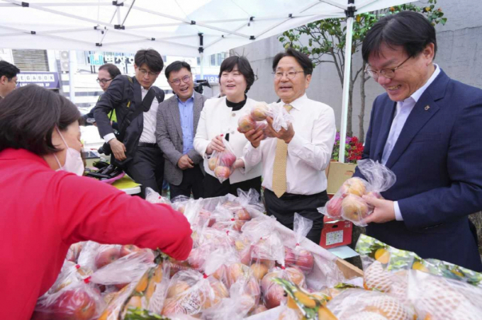 강기정 광주광역시장이 12일 오전 광산구 농협광주지역본부 주차장에 마련된 ’농축산물 금요직거래장터 개장식‘에 참석해 시민에게 과일 등을 소개하고 있다./사진=광주시 