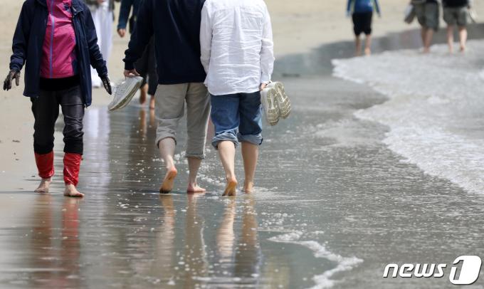 초여름 날씨를 보인 12일 오후 부산 수영구 광안리해수욕장을 찾은 시민 등 관광객들이 맨발로 해변을 거닐고 있다. 2024.4.12/뉴스1 ⓒ News1 윤일지 기자
