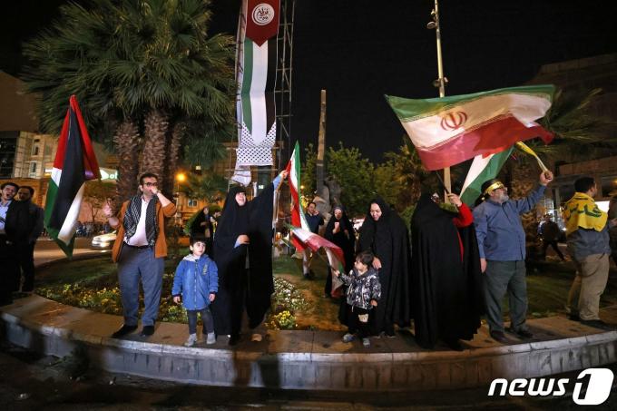 14일(현지시간) 이란 테헤란의 팔레스타인 광장에서 시민들이 이란과 팔레스타인 국기를 흔들며 이스라엘에 대한 보복 공격을 자축하고 있다. 2024.04.14 ⓒ AFP=뉴스1 ⓒ News1 정지윤 기자