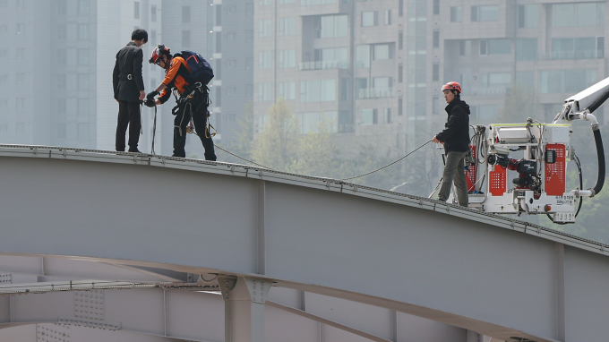  경찰은 한강대교 위에서 투신 소동을 벌인 50대 남성이 3일 전 올림픽대로에서 비슷한 소동을 벌인 것으로 추정 중이다. 17일 오전 서울 한강대교 노량진 방면에서 교량 위에 올라가 소동을 벌이고 있는 신원을 알 수 없는 남성이 현장에 출동한 소방대원의 설득 끝에 내려올 준비를 하고 있는 모습. /사진=뉴스1