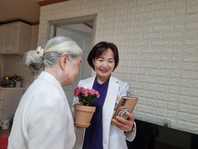 하남시에 거주하는 한 어르신이 방문간호사가 ‘마음속 새싹 가꾸기’ 프로그램 진행을 위해 전달한 꽃 화분을 바라보며 환하게 미소 짓고 있다. /사진제공=하남시