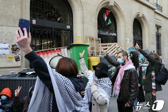 친팔레스타인 시위대가 26일 프랑스 최고 명문 시앙스포 파리(Sciences Po Paris· the Institute of Political Studies) 학교 건물을 점거한 채 출입구를 바리케이드로 막고 있는 동료들에게 승리의 V자를 표하고 있다. ⓒ AFP=뉴스1 ⓒ News1 정지윤기자