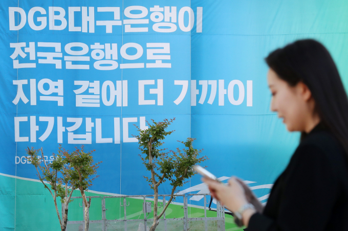  16일 오후 대구 수성구 대구은행 본점 앞 열린광장에서 은행 직원이 '대구은행의 시중은행 전환 인가'를 축하하는 현수막 앞을 지나고 있다./사진=뉴스1