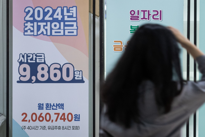 서울 마포구 서부고용복지플러스센터에 놓인 2024년도 최저임금 안내문 앞으로 한 시민이 지나고 있다. 내년 최저임금 심의를 위한 최저임금위 첫 전원회의는 오는 21일 열릴 예정이다. / 사진=뉴스1 유승관 기자