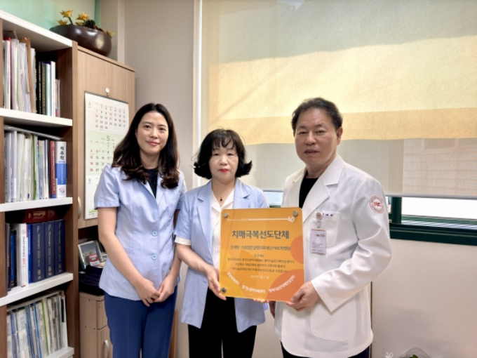박진규 PMC박병원 원장(오른쪽)이 송탄보건소 관계자로부터 2024년 치매극복 선도단체 지정서를 전달받고 있다. / 사진제공=평택시