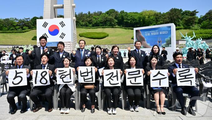 광주시의회 5·18특별위원회 위원들이 18일 광주 북구 국립5·18민주묘지에서 5·18민주화운동 제44주년 기념식을 마친 뒤 '5·18 헌법 전문 수록'이라고 적힌 손팻말을 들고 있다. (공동취재) 2024.5.18/뉴스1 ⓒ News1 안은나 기자