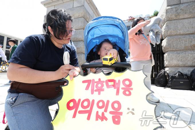 21일 오후 서울 종로구 헌법재판소 앞에서 기후 헌법소원의 마지막 공개변론을 앞둔 환경단체 기자회견에서 한 회원이 아기와 함께 참석하고 있다. 2024.5.21/뉴스1 ⓒ News1 신웅수 기자