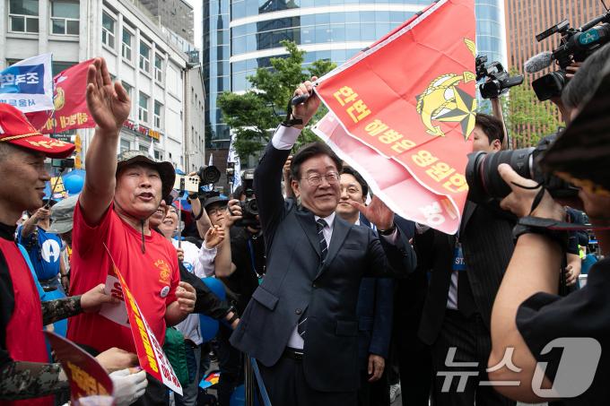 이재명 더불어민주당 대표가 25일 오후 서울 중구 숭례문 인근에서 열린 범야당 및 시민사회 '채상병 특검법 거부 규탄 및 통과 촉구 범국민대회'에 참석하며 해병대 예비역들과 인사하며 해병대 깃발을 들어보이고 있다. 2024.5.25/뉴스1 ⓒ News1 이승배 기자