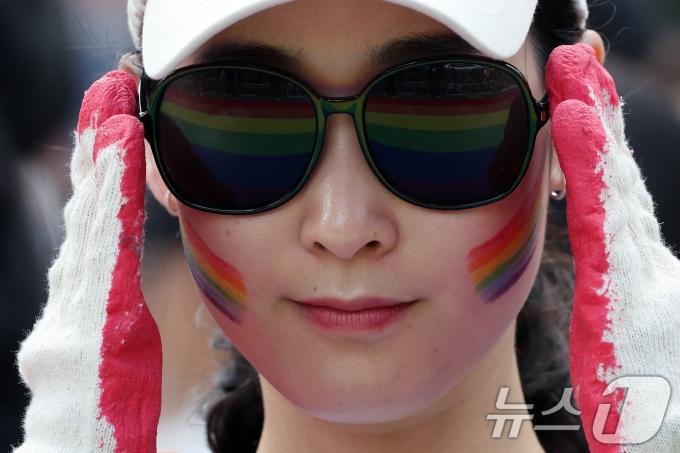 1일 오후 서울 종각역 일대에서 열린 '2024 서울퀴어문화축제'를 찾은 한 시민의 선글라스에 무지개 깃발이 비치고 있다. 2024.6.