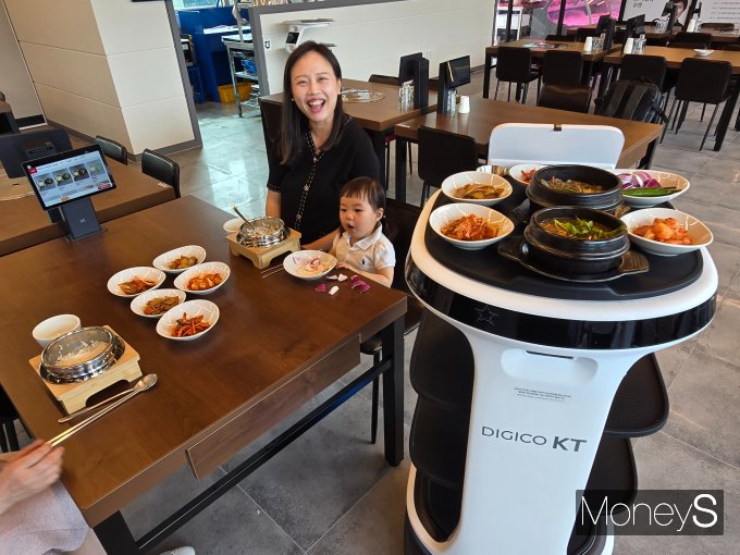 여수 음식백화점 '여수관'에을 방문한 한 가족이 서빙로봇과 하이오더를 체험해보며 즐거워하고 있다/사진=KT전남·북광역본부 제공.