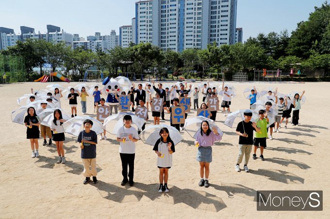  이동훈 광주신세계 대표와 김이강 서구청장, 조명숙 상무초등학교 교장, 김재춘 초록우산 광주가정위탁지원센터장, 상무초등학교 학생들이  12일 광주 서구 상무초등학교에서 '환생우산' 전달식을 진행하고 있다/사진=광주신세계 제공.