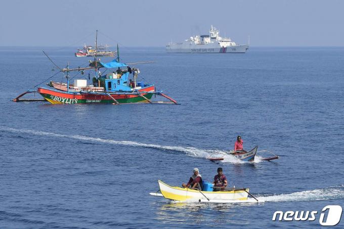 지난 21일(현지시간) 중국 해안경비대 함정이 남중국해(서필리핀해) 스카버러 암초(중국명 황옌다오·필리핀명 바조데마신록) 인근에서 조업하는 필리핀 어선들 옆을 지나가고 있다. 2023.9.25. ⓒ AFP=뉴스1 ⓒ News1 김기성 기자