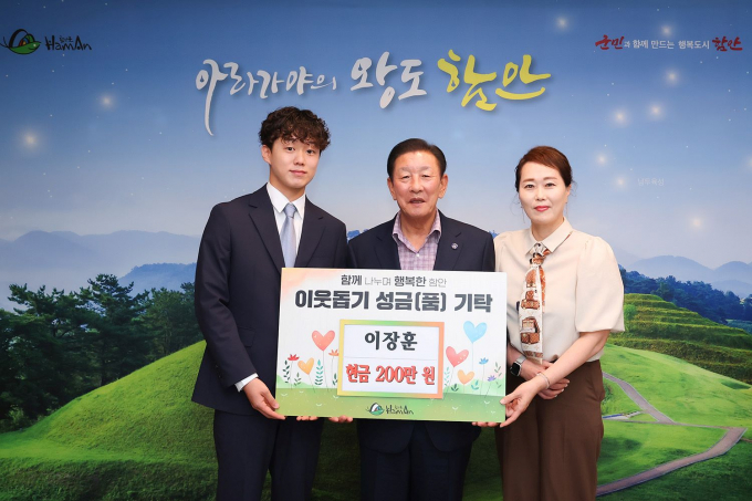 전국노래자랑 인기상을 수상한 이장훈 학생(왼쪽)이 함안군에 성금을 전달하고 조근제 함안군수(가운데)와 함께 기념촬영을 하고 있다./사진=함안군