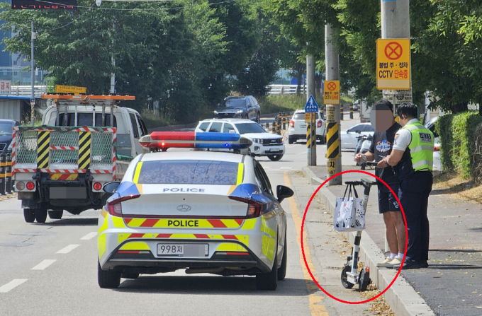 최근 전동스쿠터 이용 인구가 증가하면서 헬멧 등 안전장비 미착용으로 인한 교통사고 발생에 대한 사회적 우려가 커지고 있는 가운데 구리시 관내 외곽도로에서 한 전동스쿠터 이용자가 경찰관의 단속에 적발돼 주의 지도를 받고 있다. /사진=이건구 기자
