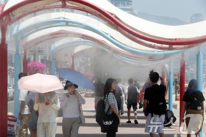 무더위가 이어진 14일 오후 부산 수영구 광안리해수욕장을 찾은 관광객들이 해변도로에 설치된 쿨링포그를 맞으며 더위를 식히고 있다. /뉴스1 ⓒ News1 윤일지 기자