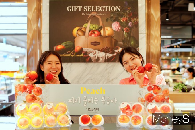 광주신세계 본관 지하 1층 식품관에서 모델들이 여름에 제철인 대극천복숭아와 옐로드림복숭아를 선보이고 있다/사진=광주신세계 제공.