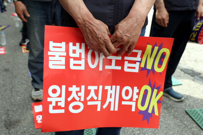 전국타워크레인 설치·해체 노조가 24일 서울 여의도 국회의사당역 앞에서 촉박한 설치·해체 작업 일정 개선과 불법하도급 문제 시정을 요구하며 무기한 파업 투쟁을 선언했다. 사진은 전국타워크레인 설치·해체 노조 총파업 결의대회에서 한 참가자가 '불법하도급 NO 원청직계약 OK'라고 적힌 손피켓을 든 모습. / 사진=뉴시스