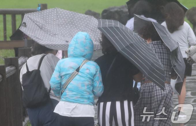 제주에 이틀째 거센 장맛비와 함께 강풍이 몰아치는 30일 오전 서귀포시 대정읍 송악산 둘레길에서 한 관광객이 쓴 우산이 뒤집히고 있다. 2024.6.30/뉴스1 ⓒ News1 오현지 기자