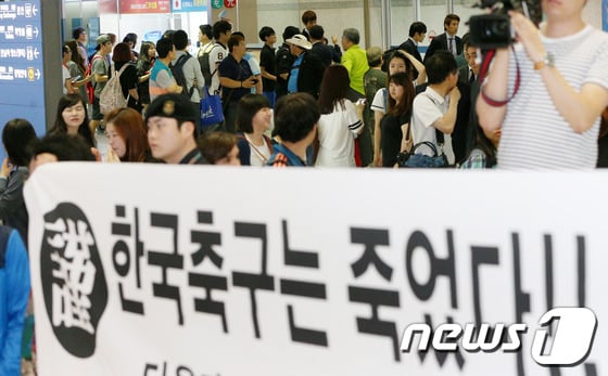 2014 브라질 월드컵에서 H조 최하위를 기록하며 16강 진출에 실패한 축구대표팀 선수들이 30일 오전 인천국제공항을 통해 귀국, 일부 팬들이 내건 '한국 축구는 죽었다!'고 적힌 현수막 뒤로 무거운 발걸음을 옮기고 있다. 뉴스1 DB