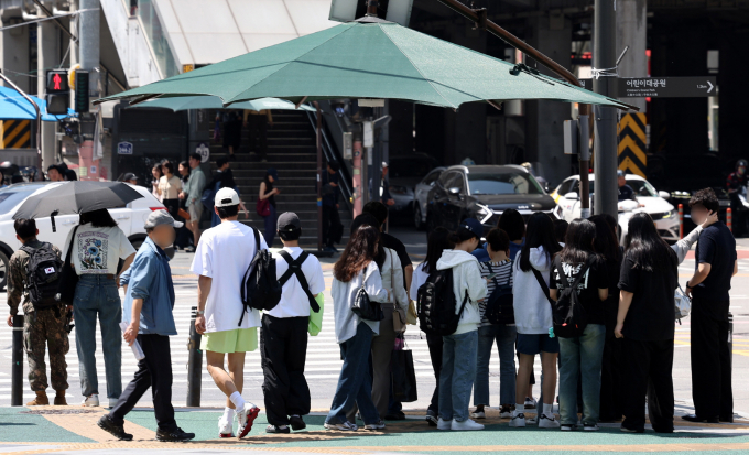 일요일인 14일은 서울 등 중부지방엔 폭염이 이어지고 제주 등 남부지방엔 천둥·전개가 동반된 폭우가 내린다. 사진은 서울 시내 한 횡단보도 앞에서 시민들이 햇빛을 피해 그늘막 아래에 모여 신호를 기다리는 모습. /사진=뉴시스