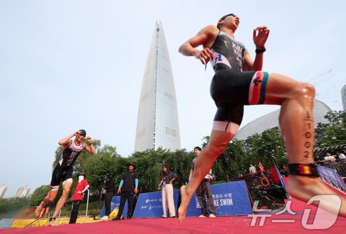 14일 오전 서울 송파구 롯데월드타워 일대에서 열린 '2024 롯데 아쿠아슬론'에 출전한 참가자들이 석촌호수에서 수영을 마치고 수직마라톤을 향해 달리고 있다.  (공동취재) 2024.7.14/뉴스1 ⓒ News1 임세영 기자