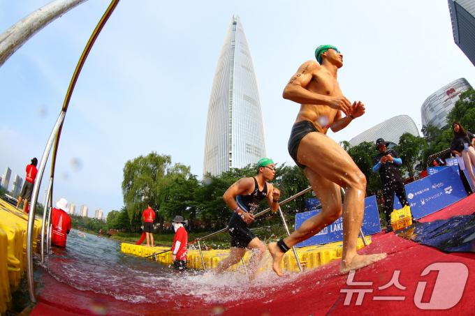 14일 오전 서울 송파구 롯데월드타워 일대에서 열린 '2024 롯데 아쿠아슬론'에 출전한 참가자들이 석촌호수에서 수영을 마치고 롯데월드타워를 향해 달리고 있다. (공동취재) 2024.7.14/뉴스1 ⓒ News1 임세영 기자