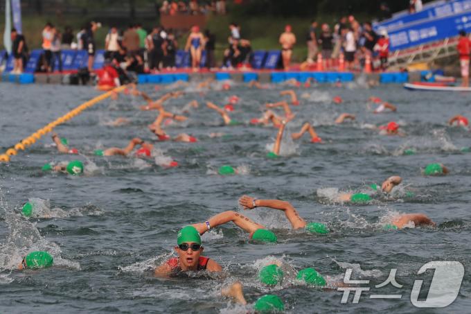 14일 오전 서울 송파구 롯데월드타워 일대에서 열린 '2024 롯데 아쿠아슬론'에 출전한 참가자들이 석촌호수에서 수영을 하고 있다. (공동취재) 2024.7.14/뉴스1 ⓒ News1 임세영 기자