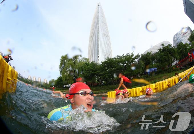 14일 오전 서울 송파구 롯데월드타워 일대에서 열린 '2024 롯데 아쿠아슬론'에 출전한 참가자들이 석촌호수에서 수영을 하고 있다. (공동취재) 2024.7.14/뉴스1 ⓒ News1 임세영 기자