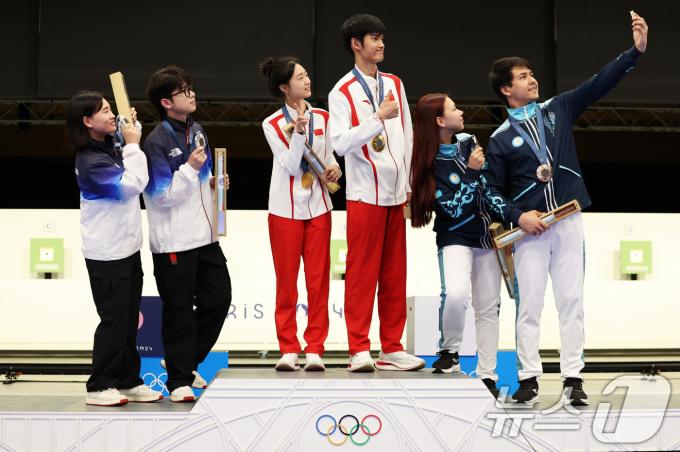 27일(현지시간) 프랑스 샤토루 슈팅센터(Chateauroux Shooting Centre)에서 열린 2024 파리 올림픽 사격 공기소총 10m 혼성 단체전 시상식에서 은메달 금지현, 박하준(이상 대한민국), 금메달 황 위팅(Yuting Huang), 성 리하오(Lihao Sheng, 이상 중국), 동메달 알렉산드라 르(Alexandra Le), 이슬람 사트파예프(Islam Satpayev, 이상 카자흐스탄) 선수들이 시상대에서 갤럭시 Z 플립6 올림픽 에디션으로 빅토리 셀피를 찍고 있다. (삼성전자·게티이미지 제공) 2024.7.29/뉴스1