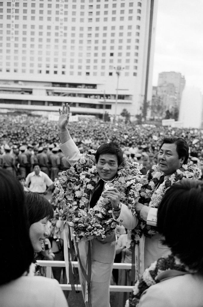 1976년 카퍼레이드를 펼친 후 환영식장에 들어선 양정모 선수. (출처: 대한민국 정부, 흑백사진(1976), Wikimedia Commons, Public Domain)