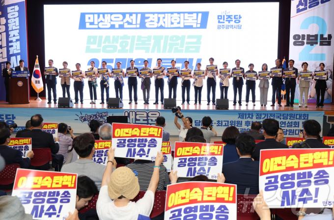 4일 광주시 김대중컨벤션센터에서 열린 더불어민주당 제1차 전국당원대회 광주지역 합동연설회에서 당대표 및 최고위원 후보 등이 '민생회복지원금 25만원, 민생우선 경제회복'이라고 적힌 손피켓을 들고 퍼포먼스를 하고 있다. 후보들 앞으로 당원들이 '이진숙 탄핵' 촉구 손팻말을 들고 있다. 2024.8.4/뉴스1 ⓒ News1 김태성 기자