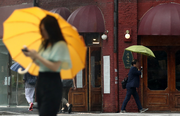8일 전국에 무더운 날씨가 예상되는 가운데 내륙 지역을 중심으로 돌풍과 천둥·번개를 동반한 소나기나 강한 비가 내릴 전망이다.  사진은 지난 7일 서울 종로구 종각역 인근 횡단보도에서 시민들이 우산을 쓴 모습. /사진=뉴스1 