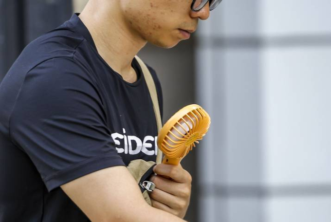 서울 종로구 세종대로에서  한 시민이 손풍기를 켜고 이동하고 있다./사진=뉴시스