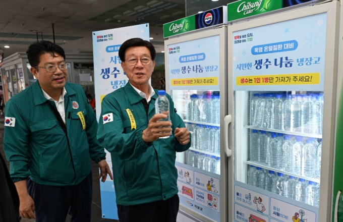 정종복 기장군수(오른쪽)가 기장시장 공영주차장에 마련된 무료 생수 나눔 냉장고의 생수를 점검하고 있다./사진=기장군