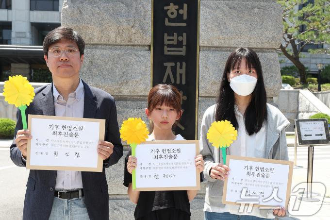 서울 종로구 헌법재판소 앞에서 기후 헌법소원의 마지막 공개변론을 앞두고 열린 환경단체 기자회견에서 시민기후소송 청구인인 황인철 씨(왼쪽부터), 청소년기후소송 청구인 김서경 씨, 아기기후소송 청구인 한제아 양이 최후진술문을 들고 있다. 2024.5.21/뉴스1 ⓒ News1 신웅수 기자