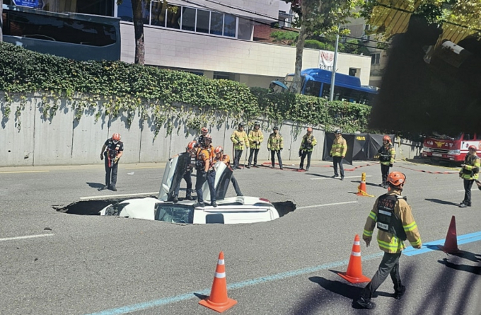 서울 서대문구 연희동 차도를 지나던 승용차가 땅꺼짐 현상(싱크홀)으로 인해 땅밑으로 빠졌다. 사진은 29일 오전 11시26분쯤 서울 서대문구 연희동 한 차도에서 싱크홀로 승용차가 빠진 모습. /사진=온라인 커뮤니티 갈무리