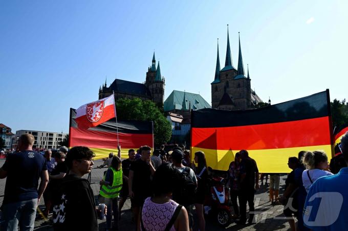 독일의 극우 정당인 '독일을 위한 대안'(AfD) 지지자들이 2024년 8월 31일 동독 에르푸르트 대성당 앞에서 거대한 독일 국기를 들고 있다. ⓒ AFP=뉴스1