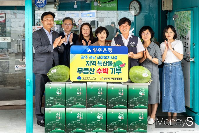 이상채 광주은행 부행장(왼쪽)은 13일 최근 무등산수박직판장을 통해 구입한 1000만원 상당의 수박 전량을 추왕석 광주 서구시니어클럽 관장(오른쪽 세번째)에게 전달하고 있다/사진=광주은행 제공.