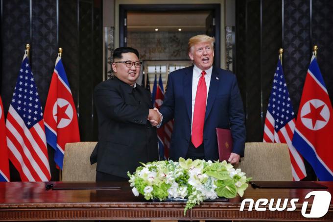 김정은 북한 국무위원장과 도널드 트럼프 미국 대통령이 12일 싱가포르 센토사 섬 카펠라 호텔에서 북미정상회담 공동합의문에 서명을 마친 뒤 악수를 나누고 있다. (싱가포르통신정보부 제공) 2018.6.12/뉴스1