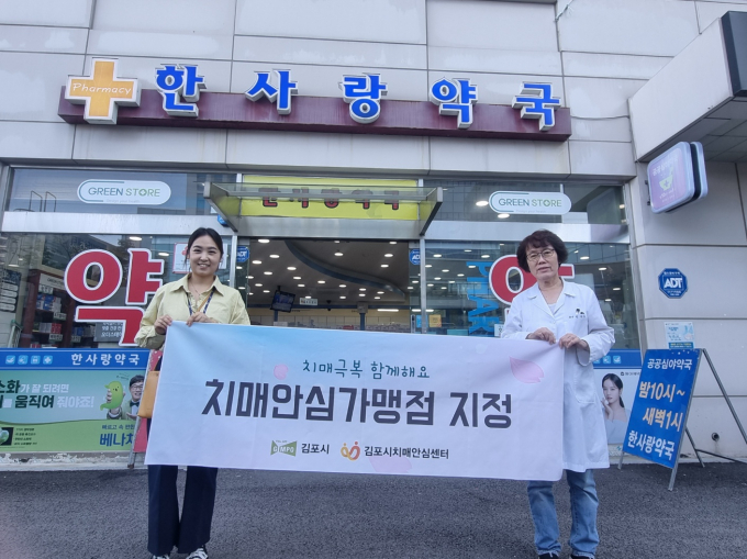 김포시치매안심센터 관계자가 '치매안심가맹점'으로 지정된 약국에 현판을 전달하고 사진촬영을 하고 있다. / 사진제공=김포시 