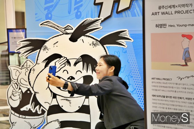 광주신세계 본관 1층에 설치된 허영만 화백의 아트월에서 방문객이 기념사진을 찍고 있다/사진=광주신세계 제공.