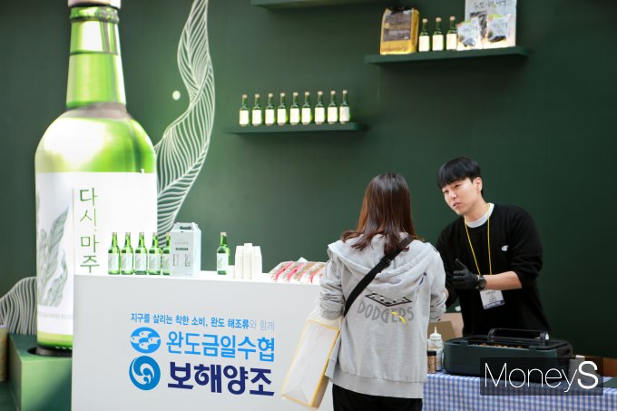 17일 광주식품대전을 찾은 한 방문객이 보해양조-완도금일수협 부스에서 '다시, 마주'를 시음하고 있다/사진=보해양조 제공.