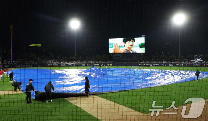 21일 오후 광주 기아챔피언스필드에서 열린 프로야구 '2024 신한 SOL 뱅크 KBO 포스트시즌' 한국시리즈 1차전 삼성 라이온즈와 KIA 타이거즈의 경기를 앞두고 비가 내리자 관계자들이 방수포를 깔고 있다. 2024.10.21/뉴스1 ⓒ News1 오대일 기자