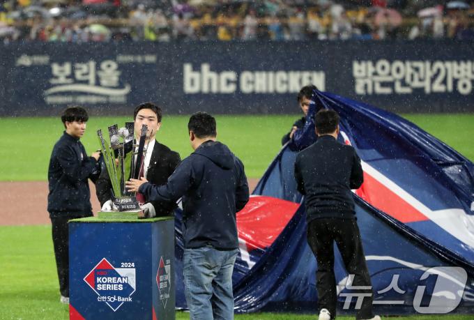 21일 오후 광주 기아챔피언스필드에서 열린 프로야구 '2024 신한 SOL 뱅크 KBO 포스트시즌' 한국시리즈 1차전 삼성 라이온즈와 KIA 타이거즈의 경기가 우천으로 지연되자 관계자들이 개막 행사를 위해 준비된 우승 트로피를 급히 정리하고 있다. 2024.10.21/뉴스1 ⓒ News1 오대일 기자