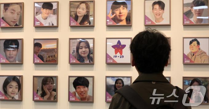 10일 서울 종로구 적선현대빌딩에 열린 '10·29 이태원 참사 기억·소통공간 이전 '별들의 집' 개소식에서 한 관계자가 희생자들의 사진을 바라보고 있다. 2024.11.10/뉴스1 ⓒ News1 김성진 기자